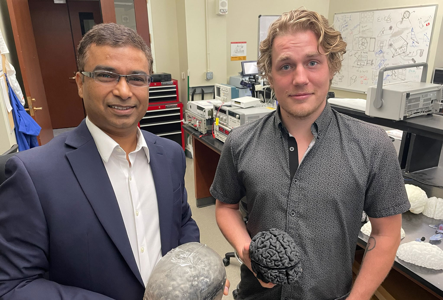 Ravi Hadimani, Ph.D., and Wesley Lohr holding models of the brain