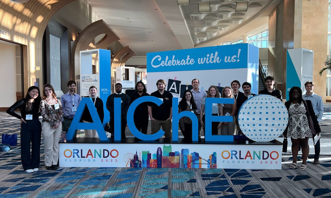 Students standing next to the AIChE sign at the annual conference in Orlando