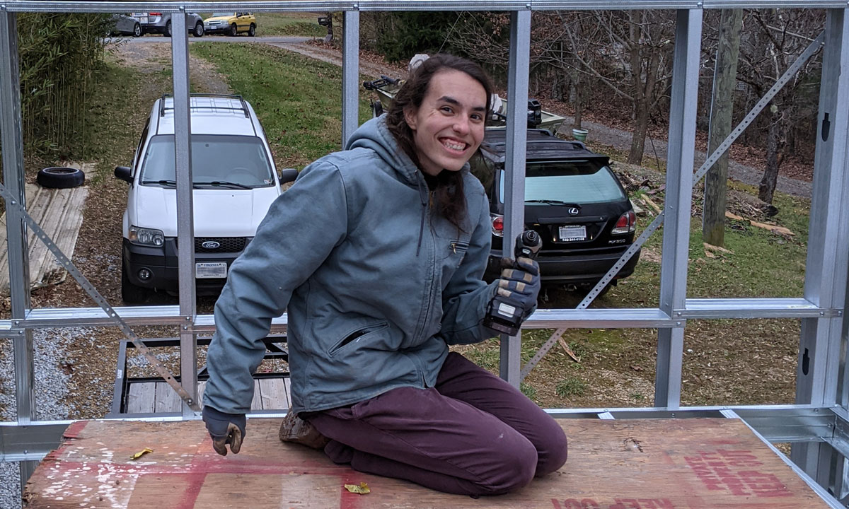 Photograph of graduate student holding power tool on building under construction.
