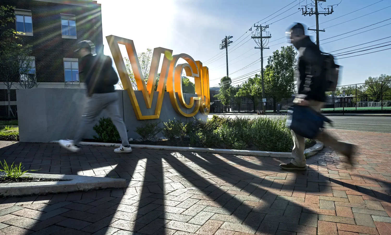 Two student walking past a VCU sign