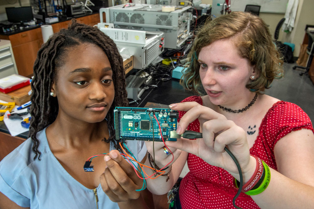 Mentor Jessi Shaffer, right, a senior majoring in electrical engineering, talks with Alexandra Wright about a micro controller that is part of Wright's project.