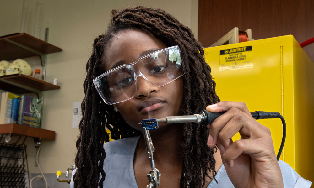 Alexandra Wright solders pinheaders on a temperature sensor at a VCU electrical engineering lab.
