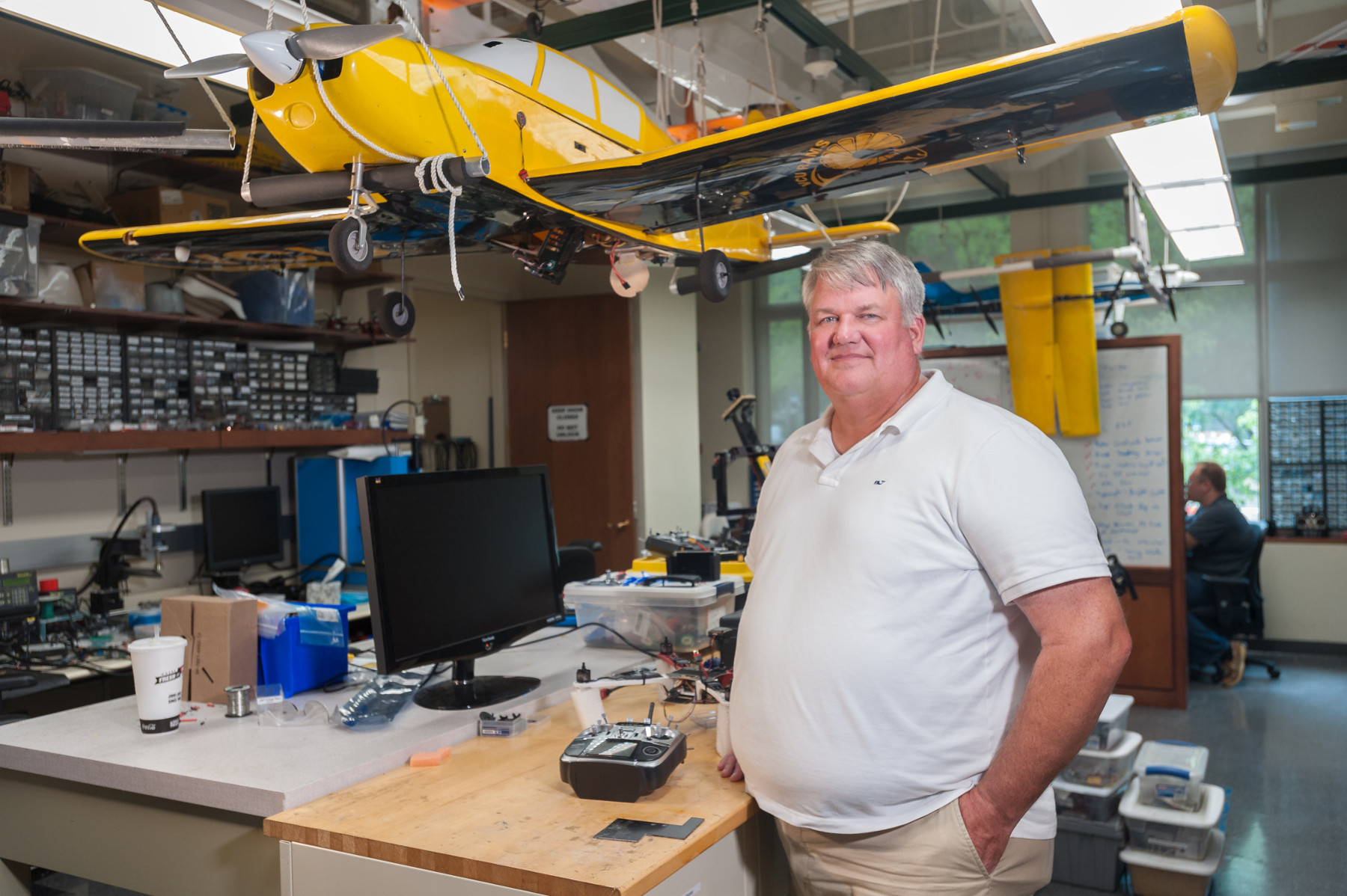 Professor standing in the UAV lab under a yellow drone.