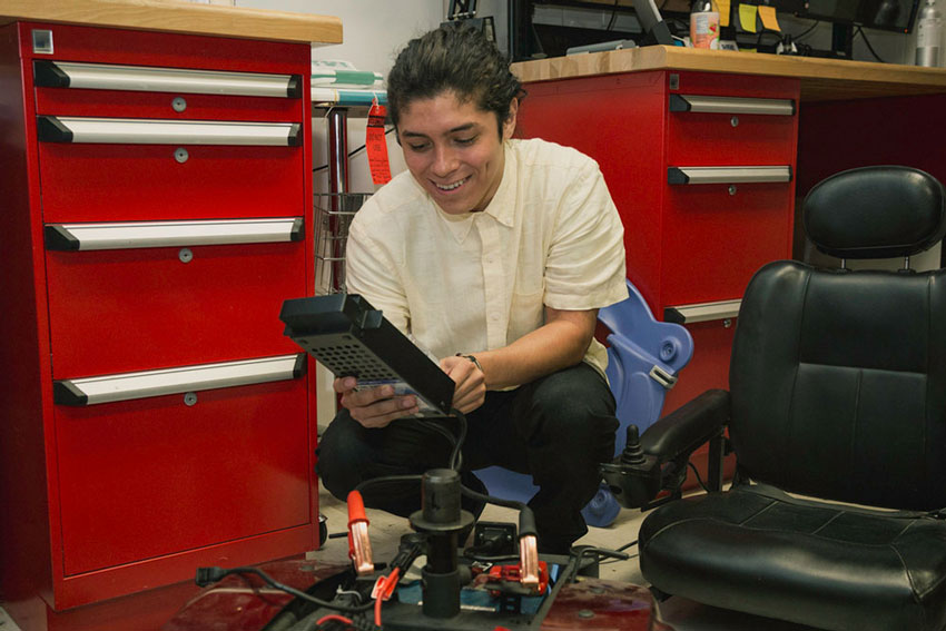 Chris Largaespada repairs a motorized wheelchair