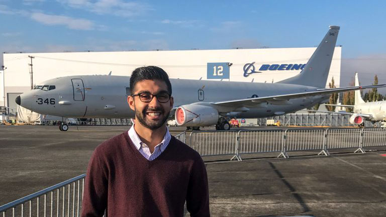Alumnus standing in front of an airline hangar with 