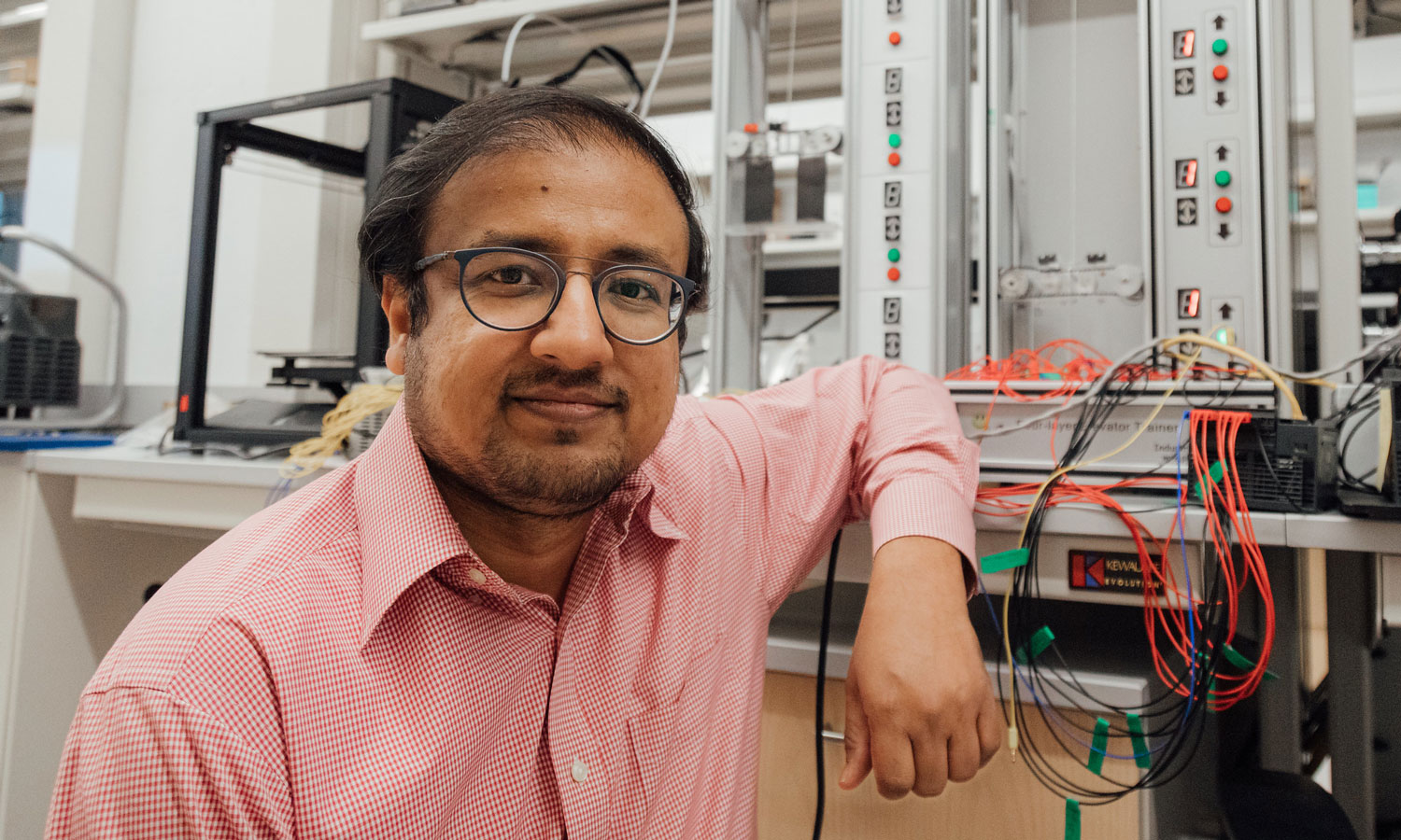 Irfan Ahmed, Ph.D., associate professor of computer science, next to a scale elevator model used to test physical systems.