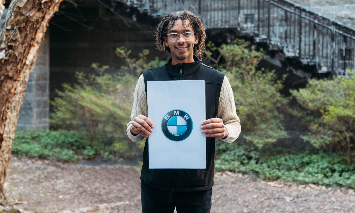 Mustafa Tewfig holding a piece of paper with the BMW logo on it