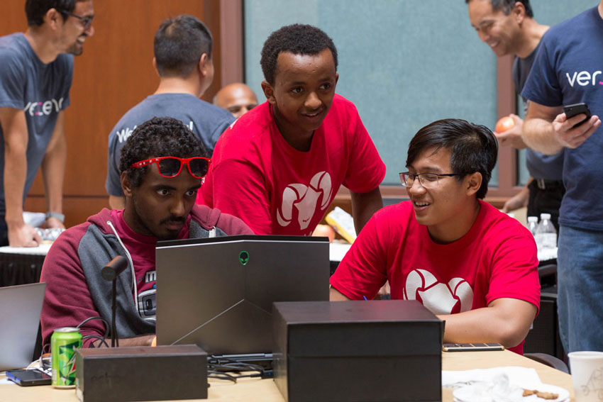 A group of students around a laptop at the annual RamHacks competition.